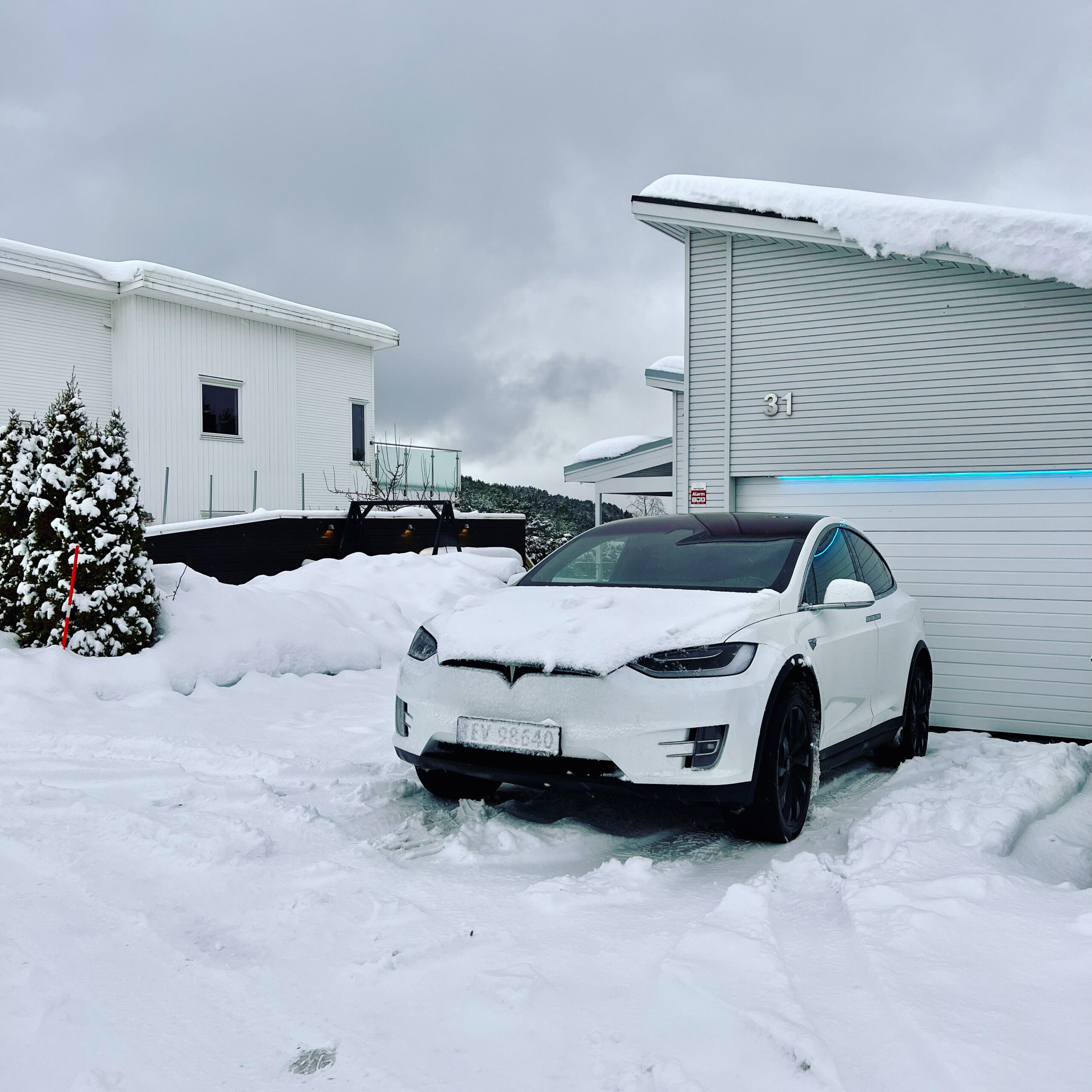 A white Tesla Model X in rought winter conditions with snow